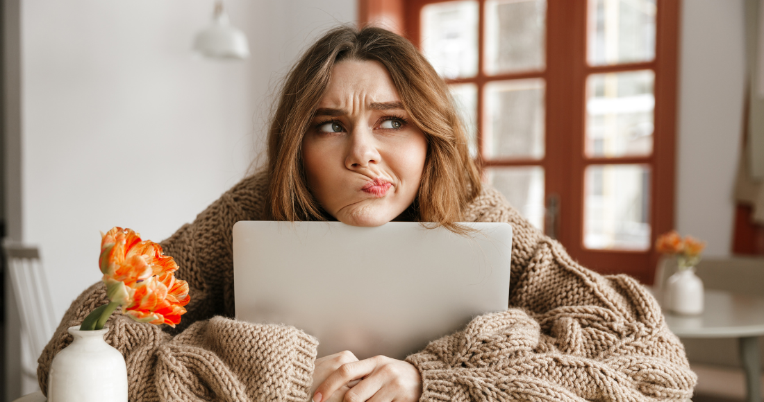 Femme pensive avec la tête posée sur son ordinateur portable.