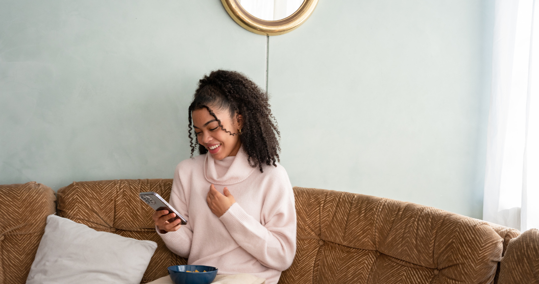 Femme qui sourit en regardant son portable.