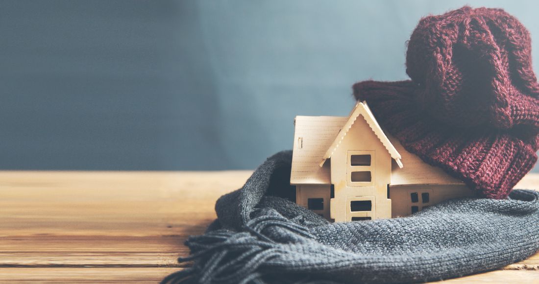 Maquette de maison avec une echarpe et un bonnet sur le bureau